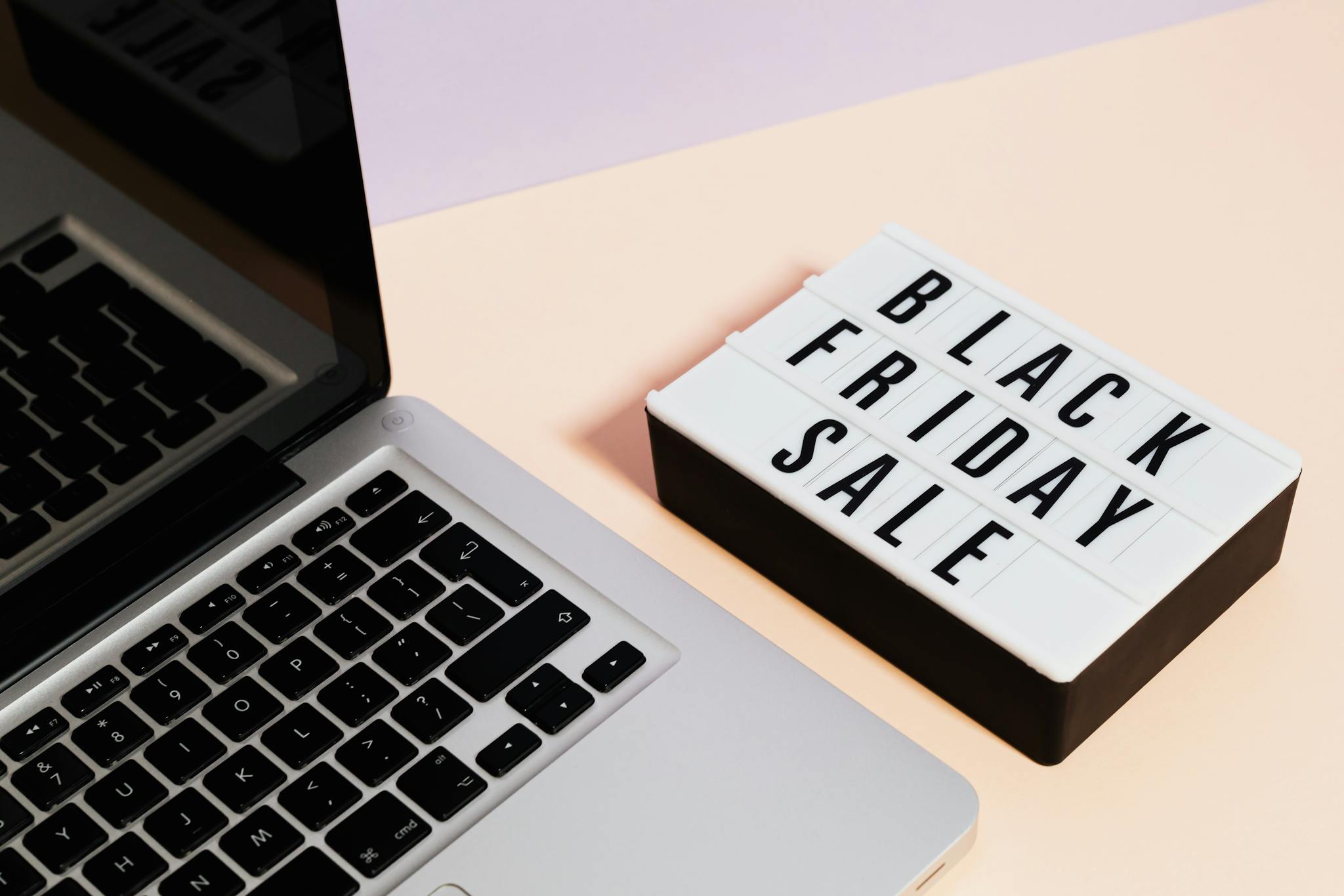 A laptop beside a lightbox sign with 'Black Friday Sale' for online shopping promotions.