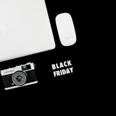 Stylish flat lay of laptop, camera, and mouse with Black Friday text.