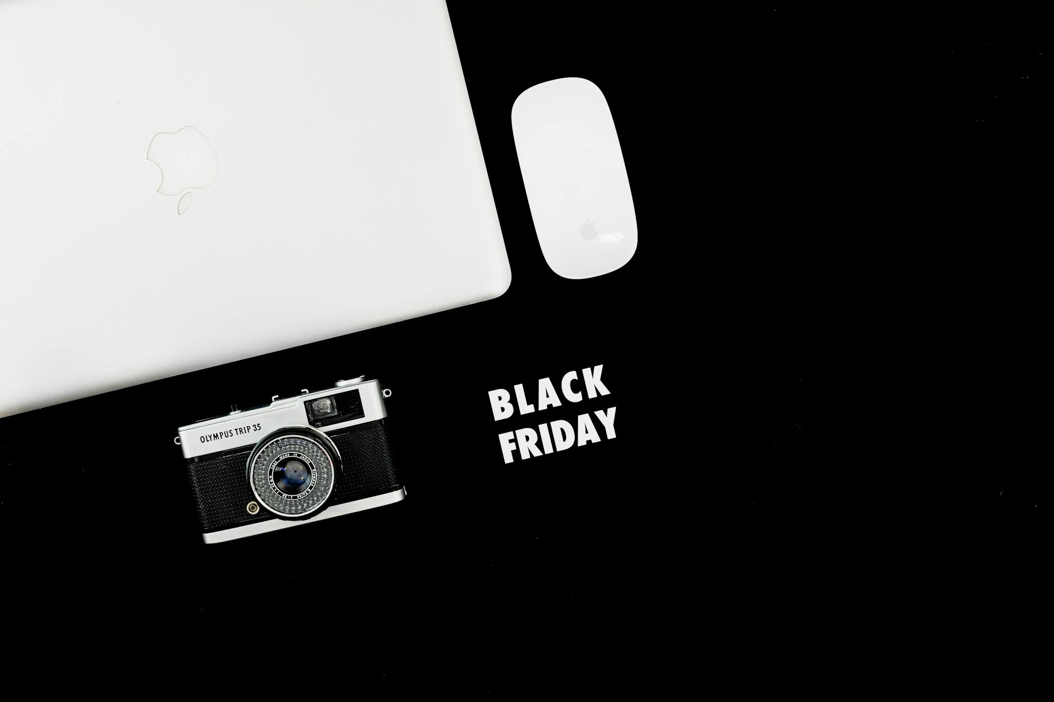 Stylish flat lay of laptop, camera, and mouse with Black Friday text.